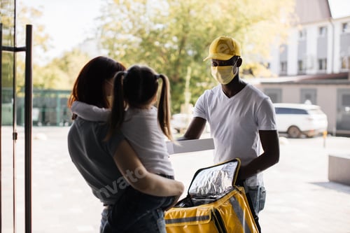 Preview: African American courier in face mask deliver to young attractive female and her daughter parcel