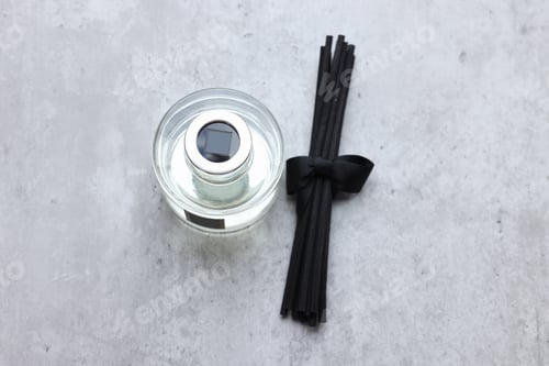 Preview: Reed sticks near glass bottle with aromatic liquid on gray marble table, flat lay