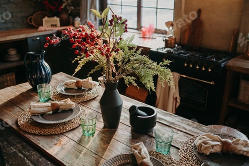 Preview: Served nicely decorated dining table with plates napkins vase. Kitchen background interior