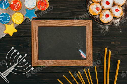Preview: top view of frame, menorah, donuts and cookies with star of david on wooden tabletop, hanukkah