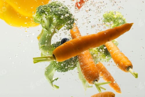 Preview: Close up of fresh vegetables falling into water with copy space on white background