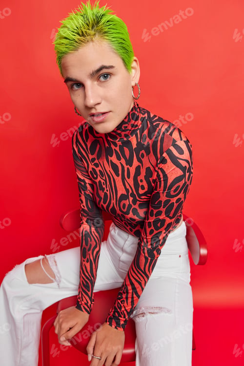 Preview: Vertical shot of serious punk girl with trendy hairstyle wears turtleneck and white jeans belongs to