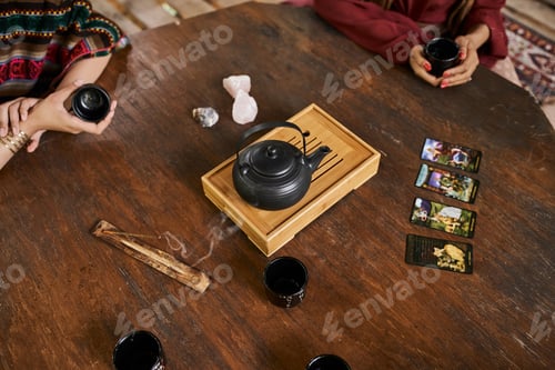 Preview: cropped view of girlfriends with tea cups, teapot, tarot cards and palo santo, women retreat concept