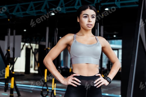 Preview: Attractive strong girl standing akimbo in fitness gym