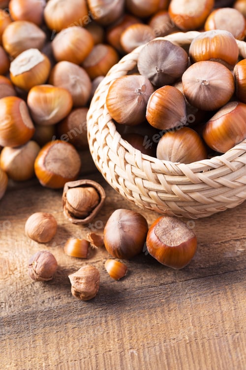 Preview: Freshly harvested hazelnuts in a woven basket on rustic wooden surface