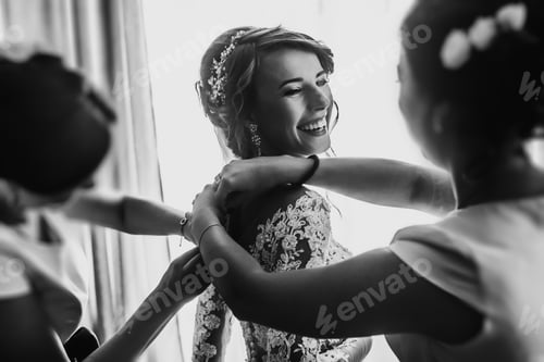 Preview: Bridesmaids helping stylish happy bride fit in dress