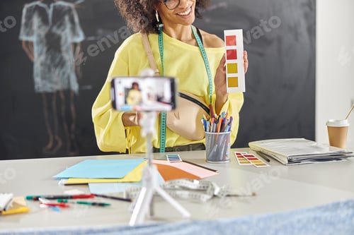 Preview: African-American fashion designer conducts online class with smartphone standing at table