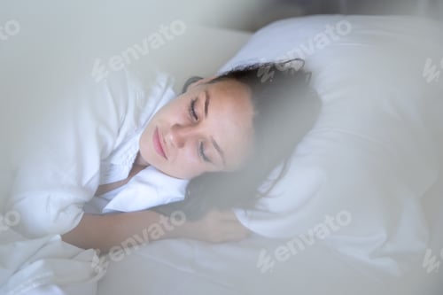 Preview: Beautiful young woman sleeping in white bed. Dreaming and relaxing time.