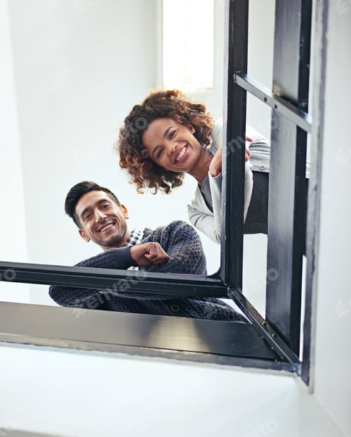 Preview: Hi from up here at the top. Low angle portrait of two coworkers leaning on a stairwell bannister.