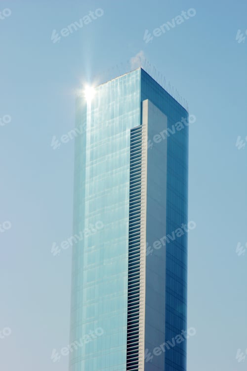 Preview: High-rise building with blue glass facade against the blue sky. Multi-storey office building.