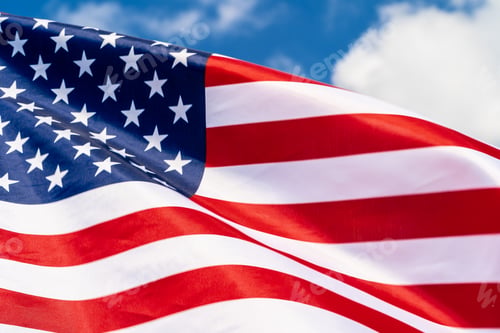Preview: American flag on flagpole waving in the wind against white clouds