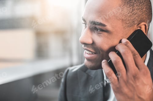 Preview: Close Up Young African Man Communicating On Mobile Phone. Focus On His Face Looking To The Side. He