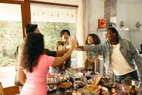 Preview: Group of happy friends holding hands together during festive home party