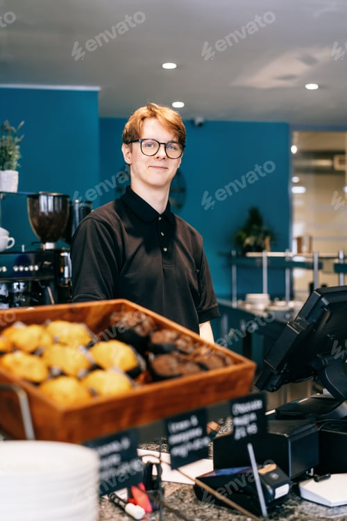 Preview: Young waiter serving customer at cash point in cafe. Man working with POS terminal. Cashier, barista