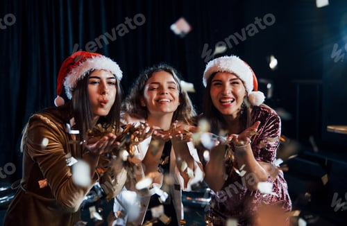 Preview: Three positive girls blowing gold colored confetti from their hands