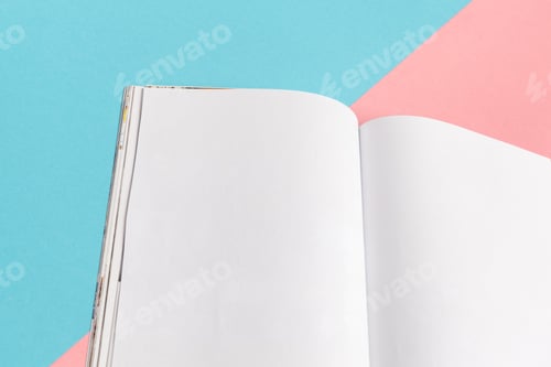 Preview: Blank pages in a notebook resting on a colorful background during daytime