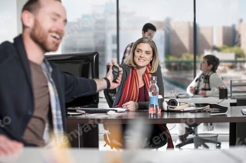 Preview: Man handing over telephone to colleague in office