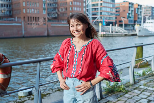 Preview: Mature smiling woman in embroidered shirt looking at camera, outdoor