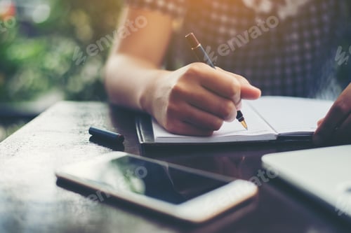 Preview: Close-up of young beautiful woman hands writing and work with laptop computer.