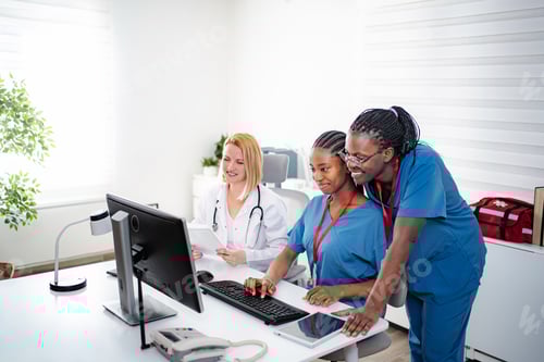 Preview: Medical team collaborating on computer in clinic office