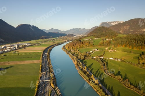 Preview: Aerial view of highway interstate road with fast moving traffic near big river in Alps mountains