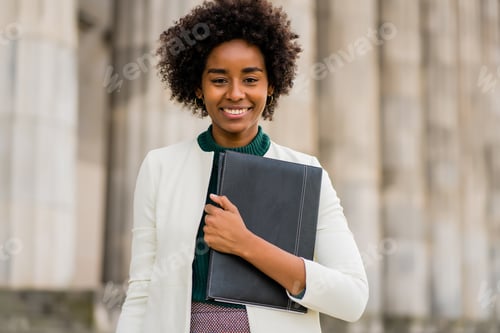 Preview: Afro businesswoman holding clipboard outdoors at the street.
