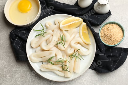 Preview: Uncooked squid rings and ingredients on grey table, flat lay