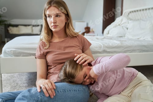 Preview: Worries mother embracing her sad elementary age girl sitting on floor