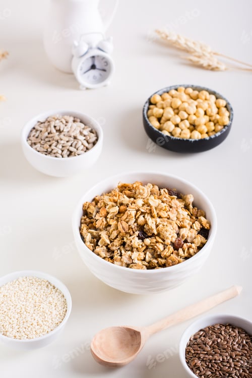 Preview: Dry granola, sesame seeds, flax seeds, sunflower seeds, chickpeas and quinoa in bowls. Vertical