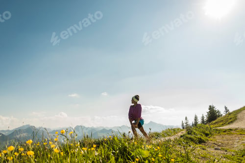Preview: Austria, Tyrol, Tannheim Valley, young woman standing in mountainscape looking at view