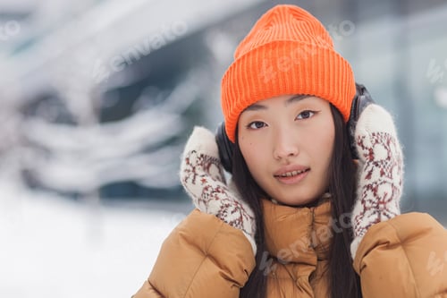Preview: Close-up portrait of a young beautiful Asian woman looking at the camera and smiling while listening