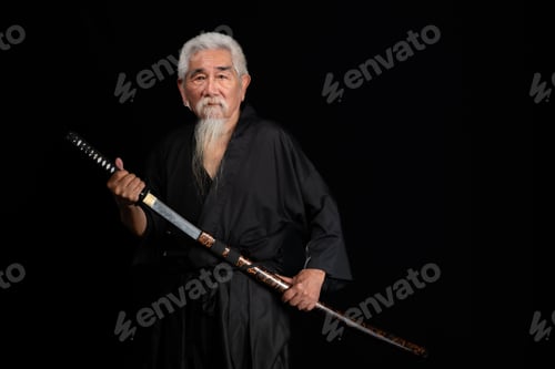 Preview: Senior Japanese samurai with katana sword on black background, studio shot
