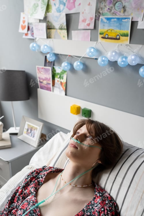 Preview: Restful teenage girl with oxygen nose pipe keeping her head on pillow