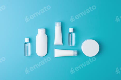 Preview: Cosmetic skin care products with flowers on blue background. Flat lay, copy space