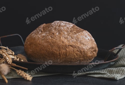 Preview: One rye round bread on a black background.