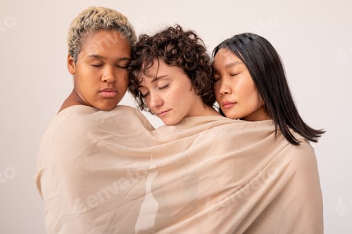 Preview: Group of young intercultural females with closed eyes wrapped into white linen