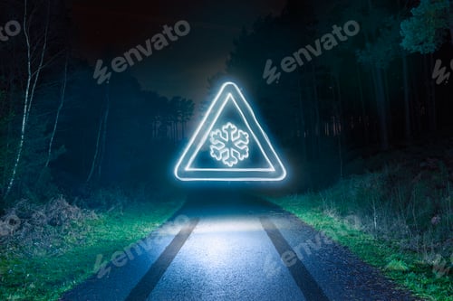 Preview: Glowing ice warning sign on a dark forest road at night