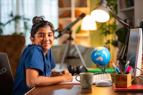 Preview: Asian Indian school girl studying at home on computer