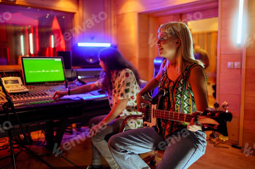 Preview: Young girl with bass guitar sitting at music studio and recording her part