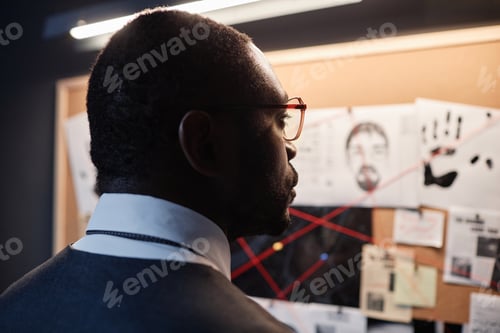 Preview: African American detective looking at evidence board investigating case