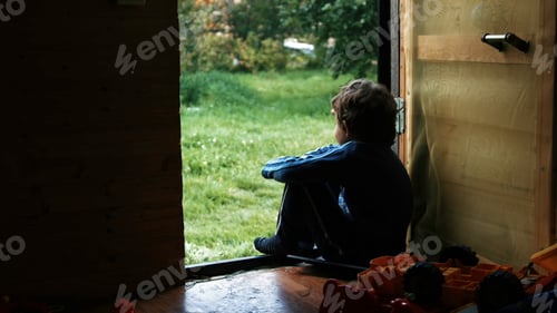 Preview: A sitting boy. Creative. A little boy who looks at the green street next to his toys in the room