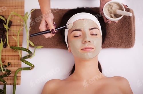 Preview: Hands of therapist apply cream to face of woman. Concept of care and youth