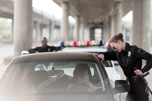 Preview: policewoman in sunglasses talking to woman sitting in car and policeman standing behind near car
