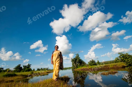 Preview: Indian woman alone in front of lake and enjoying the colors of nature.