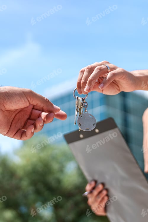 Preview: Unseen real estate agent handing over keys to delighted buyer, marking a new beginning