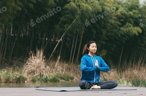 Preview: Young Asian woman doing yoga outdoors