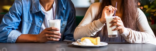 Preview: Two People Sitting at Table With Cup of Milkshake, Cropped