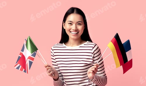 Preview: Learn Languages Online. Happy Asian Woman Holding International Flags And Using Laptop