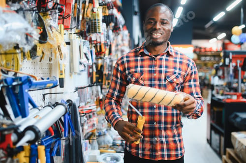 Preview: African american male customer in a modern hardware store chooses a paint roller