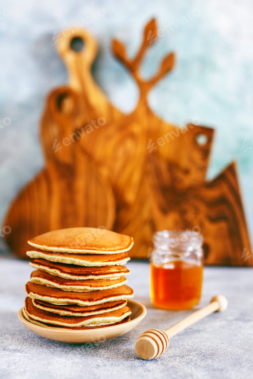 Preview: Stack of homemade pancakes with honey syrup and berries.